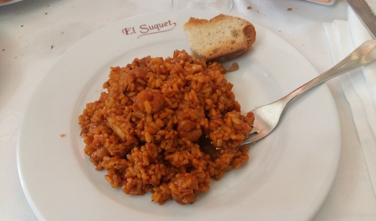 Plato de arroz servido en un plato con el logo de El Suquet