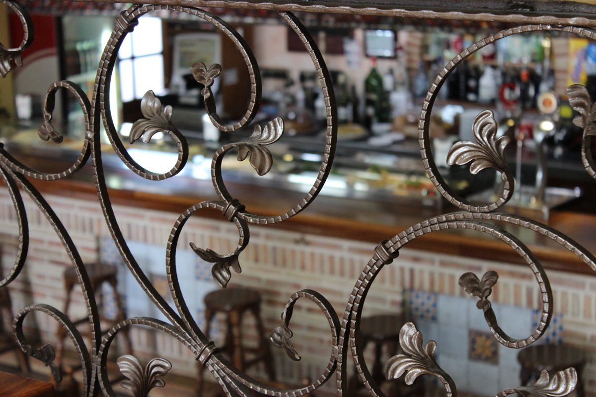 Reja de forja de la escalera con la barra del bar al fondo