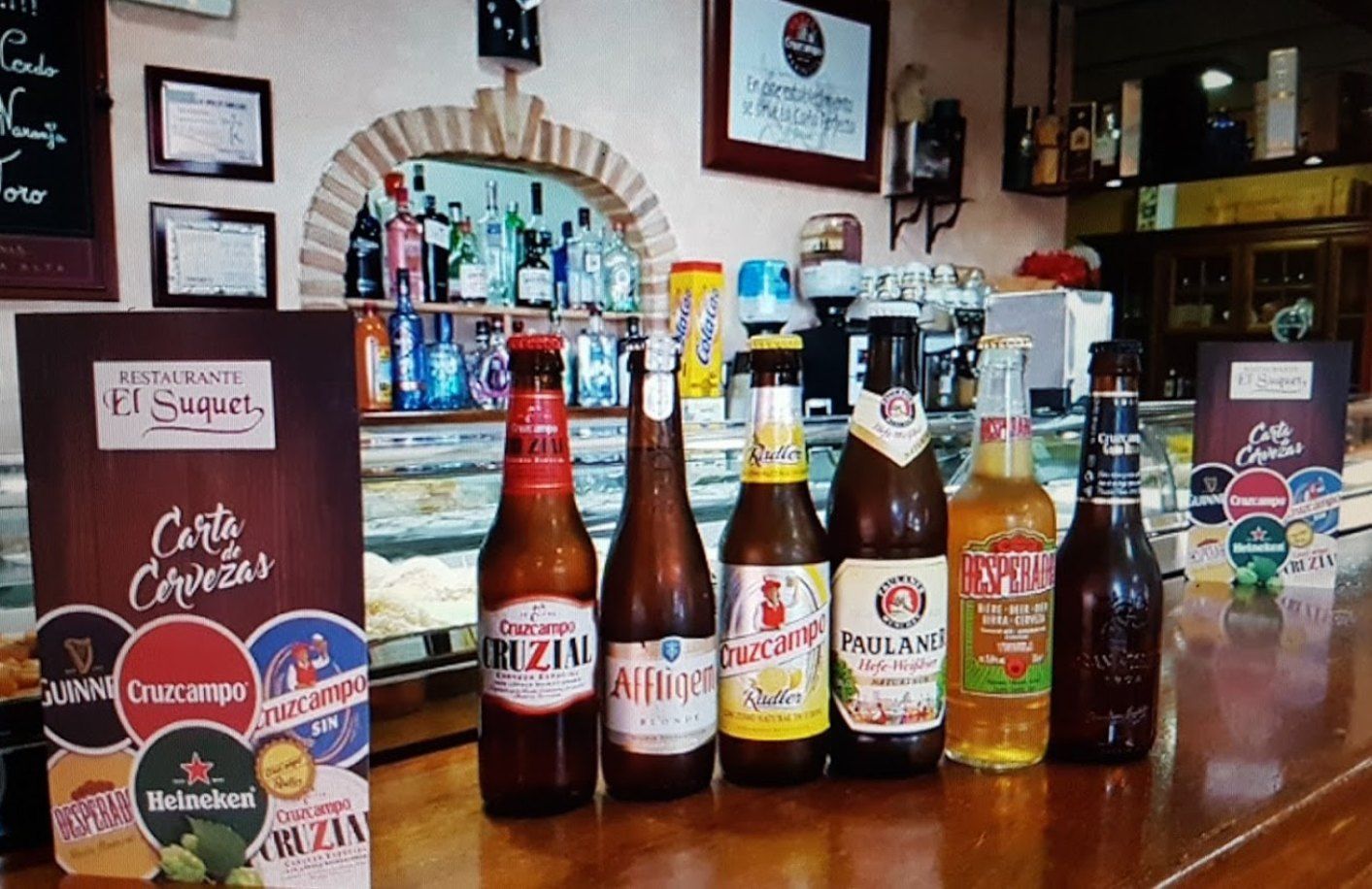 Botellas de cerveza sobre la barra junto a la carta de cervezas de El Suquet
