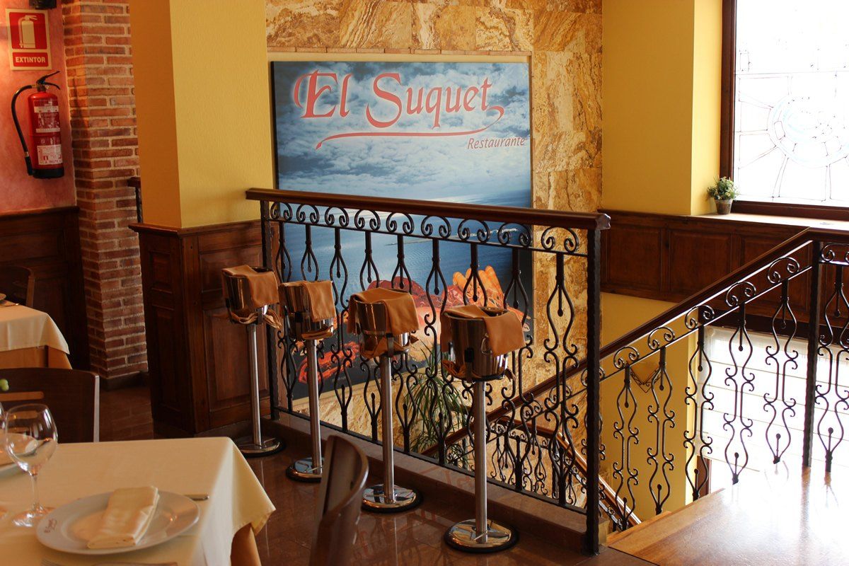 Escalera con barandilla de forja y cuadro de El Suquet junto al salón