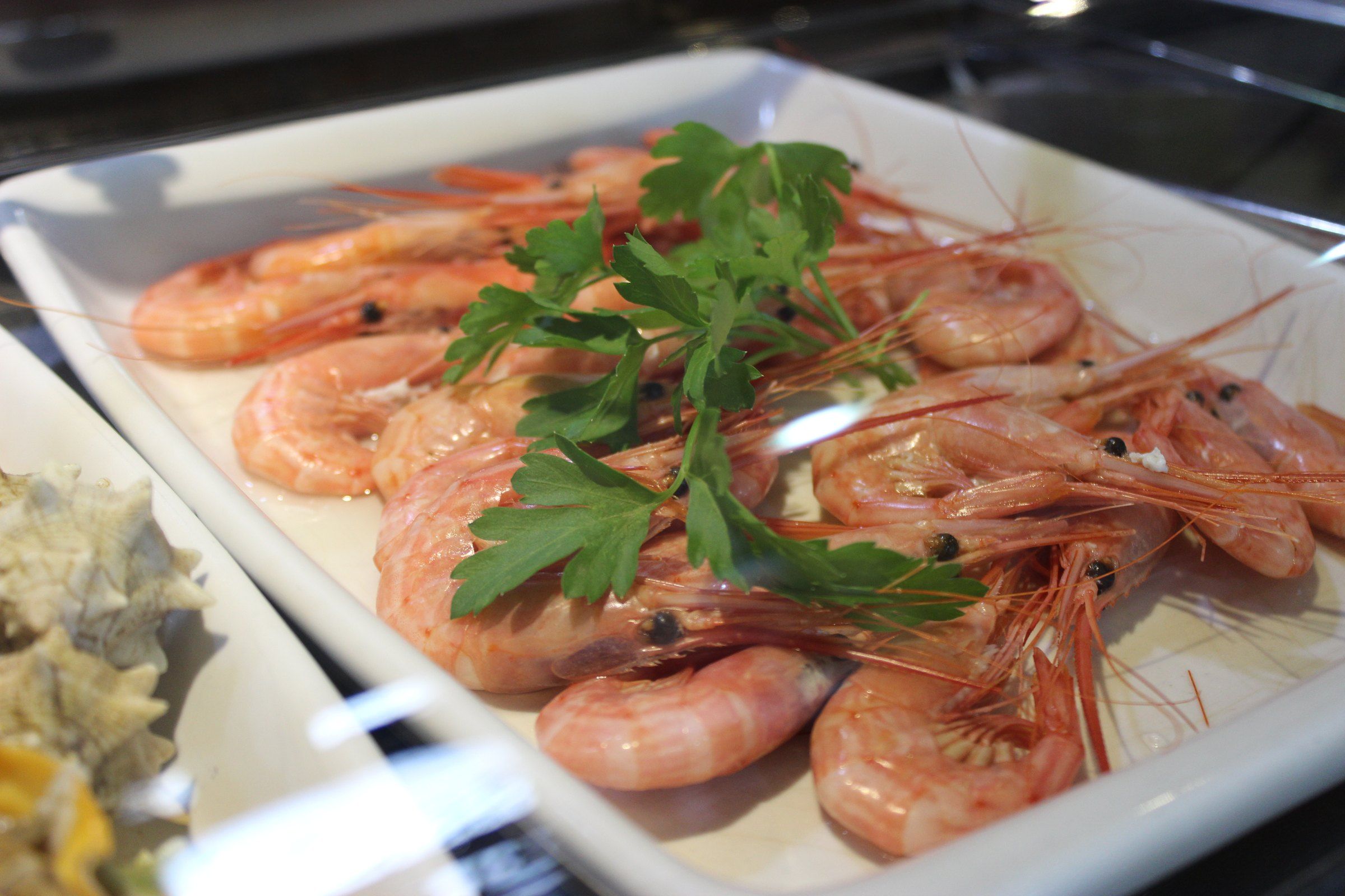 Bandeja de gambas cocidas con perejil en la vitrina de El Suquet