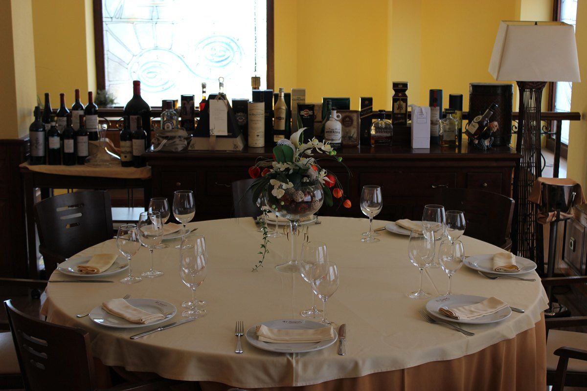 Mesa redonda montada para una celebración, con la bodega de vinos detrás