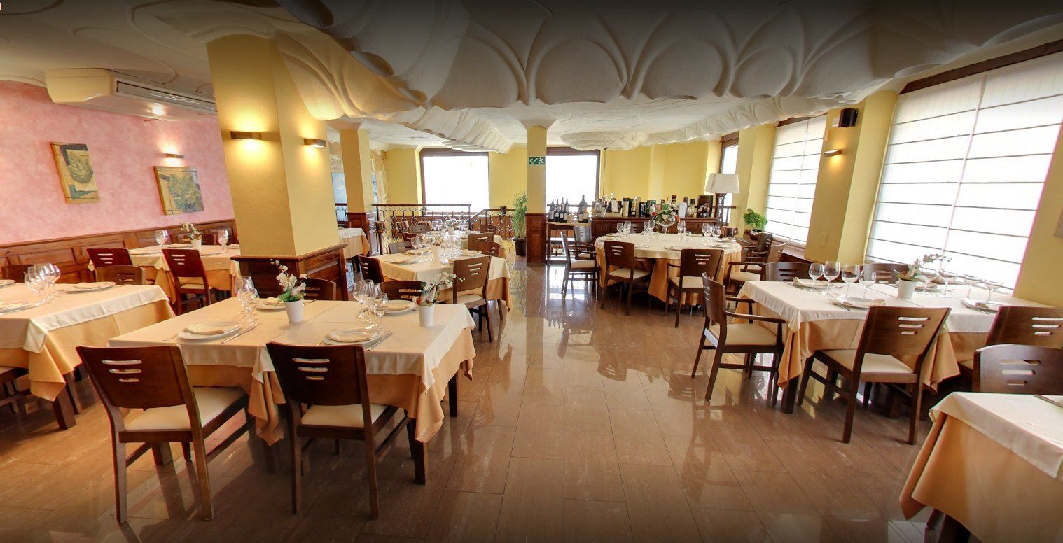 Salón de la primera planta de El Suquet con mesas vestidas y ventanales
